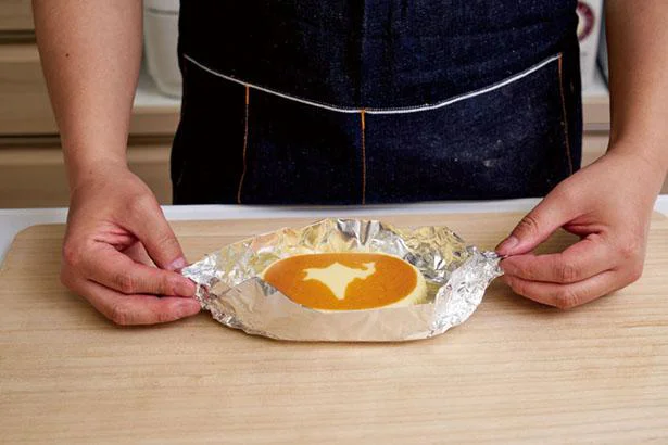 【画像を見る】北海道チーズ蒸しケーキのペーパーをはずしてアルミホイルの上にのせる