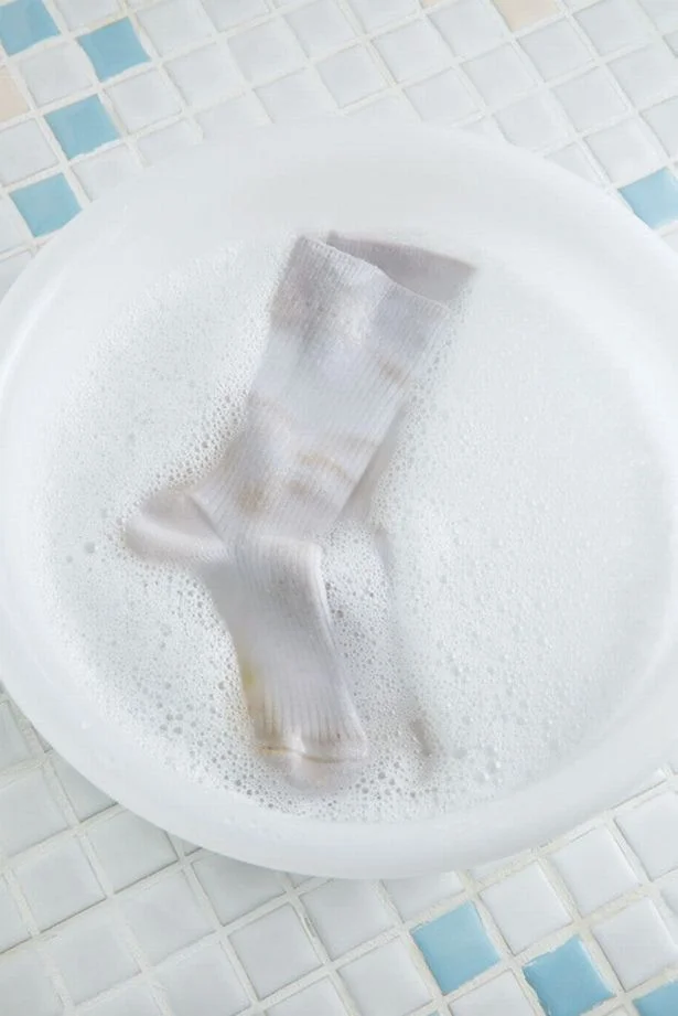 【写真を見る】靴下をはたいて泥を落としてから、40℃の湯に粉末洗剤を溶かした液の中に1時間ほどつけ置く
