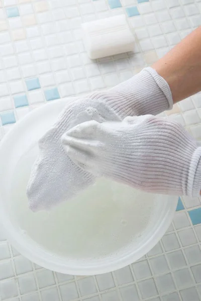 靴下を両手にすっぽりかぶせ、洗濯用固形石けんをこすりつけてゴシゴシ洗う。同様に40℃の湯でこすりすすぎ。あとはほかの洗濯物と一緒に洗濯機で洗って