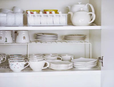 食器棚にコの字ラックを入れ、上にもスペースを作る。急須、コーヒーカップなどお茶セットとともにお皿を収納。