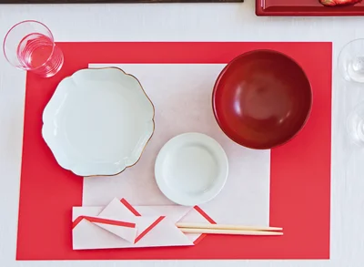 赤い画用紙に天ぷら用の敷き紙を重ねて、お正月仕様のランチョンマットに。鮮やかなのに落ち着いた感じを出すことができます。