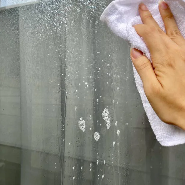 雨でぬれた窓を雑巾で拭き