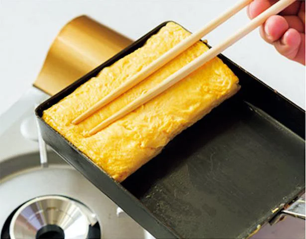 卵を箸で卵焼き器に押しつけるようにして形を整える