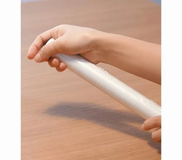 ２．ラップの筒を掌で包み込むように握り、輪ゴムがラップの端に引っかかるように手首を返したり戻したりを繰り返します。