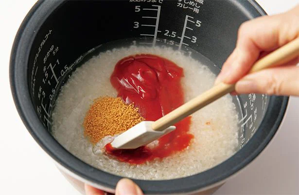 米の上に、ケチャップ、コンソメを入れてゴムべらでまぜる。