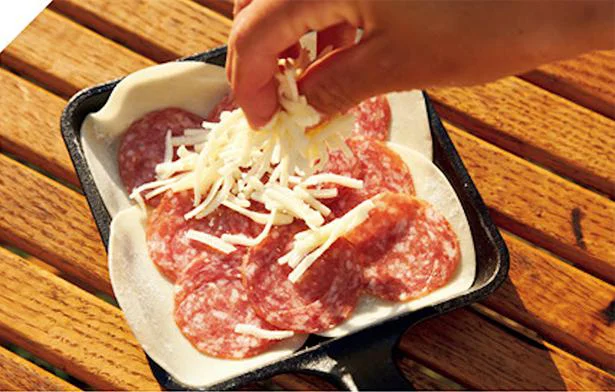 小さめの四角いフライパンにオリーブオイルをひき、餃子の皮を並べ、ソース、サラミ、チーズをのせる