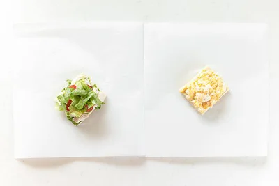 作り方８：オーブンシートの上に高野豆腐を1枚ずつ置く。レタス・ささみ・ミニトマト、たまごをそれぞれに乗せる。
