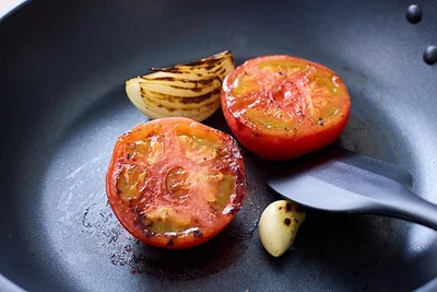 フライパンに油をひかずにトマト、玉ねぎ、にんにくを入れ、強めの中火で焦げ目がつくまで焼く
