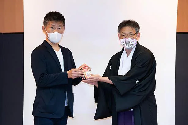 パナソニックの西明寺さん（左）から花園神社の片山宮司へパルックLEDが渡される