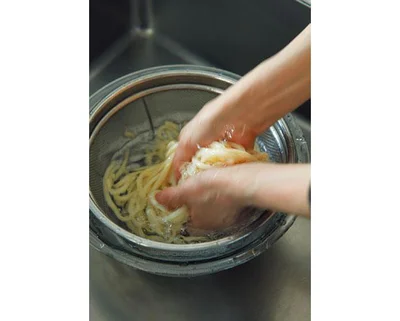 麺が冷えたらざるをボウルに重ねて水を入れ、両手でもむようにしてうどんのぬめりを取る。
