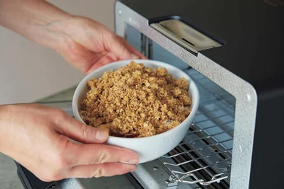 耐熱皿にカステラを敷き詰め、レンチンしたりんごを入れたら、クランブルを全体にのせてオーブントースターへ