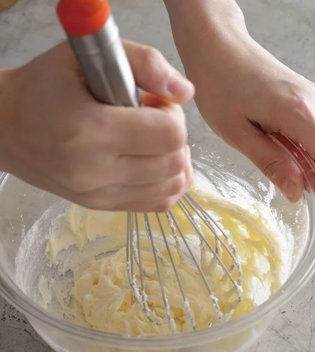 バターを入れて泡立て器で混ぜてなめらかにし、砂糖を加えてすり混ぜる