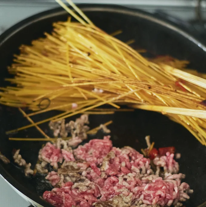 スパゲッティを半分に折って加え、時々上下を返しながら、トマトがなじむまで焼きつけるようにして炒める。