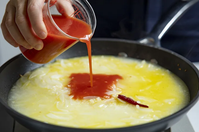 炒めた米にトマトジュースを加えて炊き、パエリャに