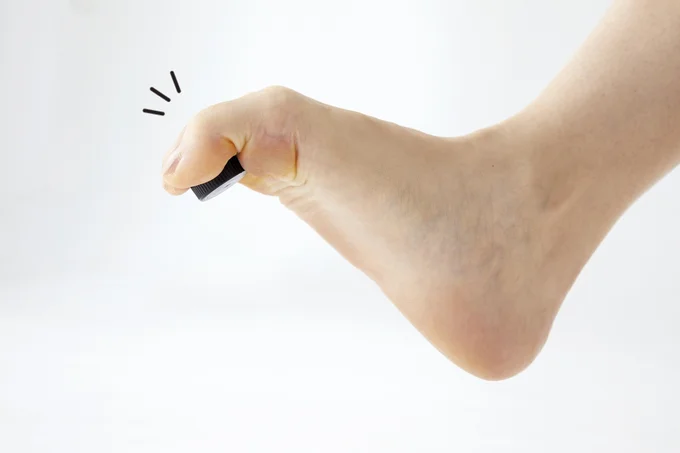 足の指で床に置いたキャップをつかみ上げる