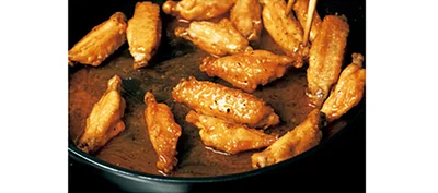 揚げた手羽先にバターやスパイスをからめ、リッチな味わいに