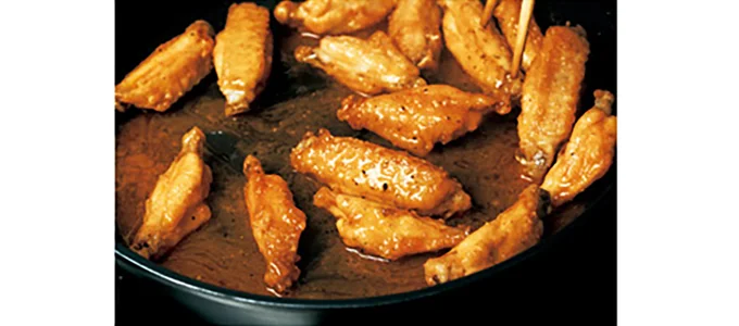 揚げた手羽先にバターやスパイスをからめ、リッチな味わいに