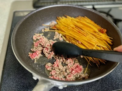 パスタを端に寄せてひき肉をざっくりほぐす