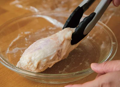 レンチンサラダチキンの作り方3　直径20cmの耐熱皿に入れ、ラップをかけて500Wで3分レンチンする。取り出して上下を返し、ラップをかけてさらに2分レンチンする。そのまま庫内に約5分おいて余熱で火を通し、取り出して粗熱をとる（皮は、粗熱がとれたら好みではがしてもOK）。（保存方法は？▶︎次へ）