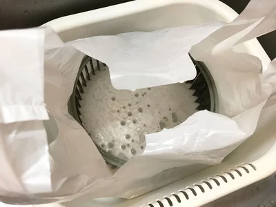 二重にしたビニル袋の中に、50℃程度のお湯を入れてオキシクリーンを溶かします。そこに換気扇を漬けおくだけです