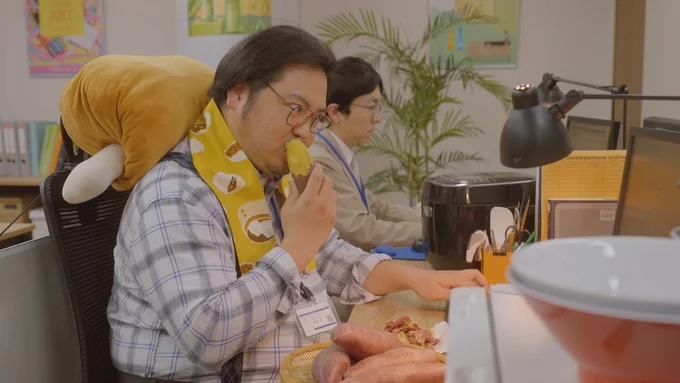 忙しい年末に焼きいもをほおばりながら仕事をこなす露の先輩、保ケ辺さん