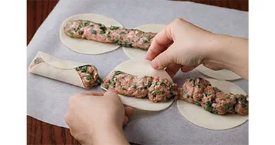 肉だねを軽く押さえて餃子の皮ごとに分け、下、上の順に皮をくっつける