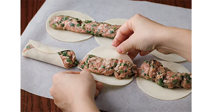肉だねを軽く押さえて餃子の皮ごとに分け、下、上の順に皮をくっつける