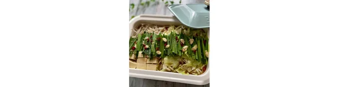 豚肉に火が通ったらニラ、ニンニク、赤唐辛子、炒りごまをのせ、仕上げにごま油をかける。