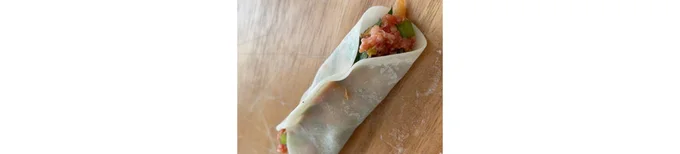 餃子の皮に大葉をのせ、その上に餃子のたねを適量のせ、ふちに水をつけて半分に折りたたむ。