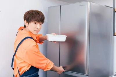 照れながら容器を冷蔵庫に入れる小山さん