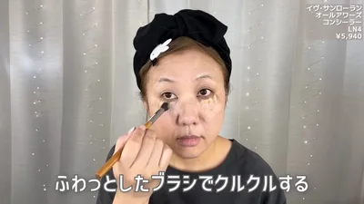 ベージュのコンシーラーを目元に乗せ、ブラシでくるくると伸ばす