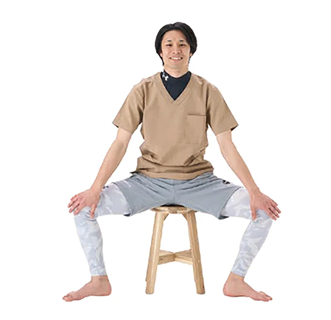 1. 椅子に浅めに腰かけ、脚を広げ、ひじを伸ばしてひざの内側に手を当てる。