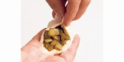 【3】手を水でぬらしてサラダ油少々をつけ、生地の1/4〜1/3量を丸める。中央をくぼませて１の1/4〜1/3量をのせ、生地の縁をのばして中央をつまんで閉じ、閉じ目を下にしてフライパンにのせる。残り2個も同様にする。