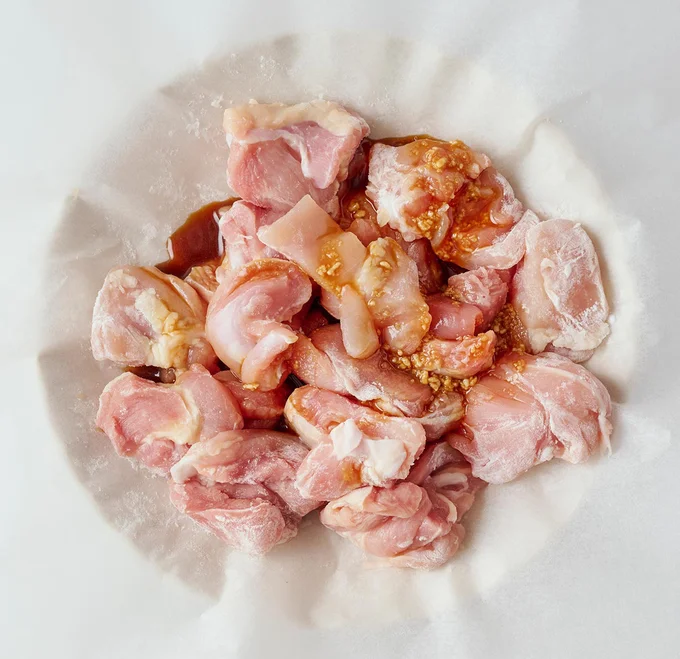 クッキングシートに鶏肉をのせて片栗粉をまぶす