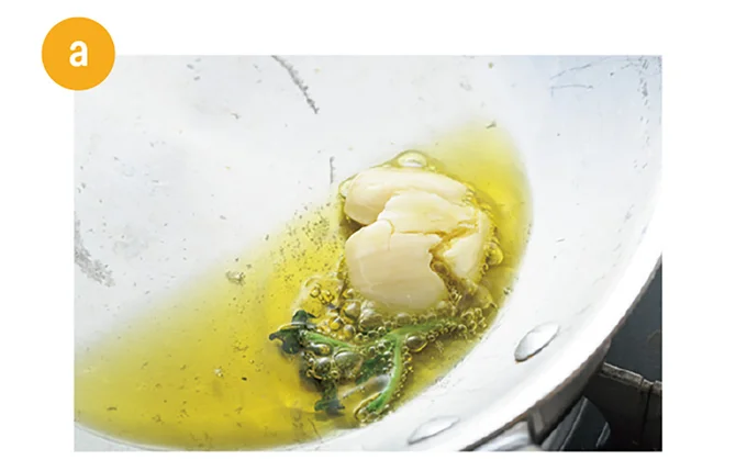 にんにくは包丁の腹などでつぶす。バジルは茎と葉を分ける。玉ねぎはみじん切りにする。フライパンにオリーブオイル、にんにく、バジルの茎を入れて弱火にかける。