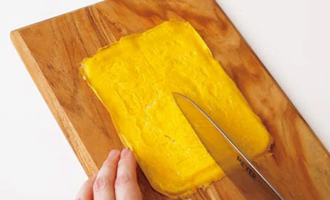 焼き上がった卵をまな板に取り出し、縦半分にカット