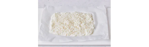 オーブン用ペーパーを20cm長さに切ってご飯をのせ、水でぬらしたスプーンで薄くのばす