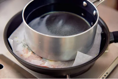 とり肉を焼くときは水を入れた鍋をのせておもしにする