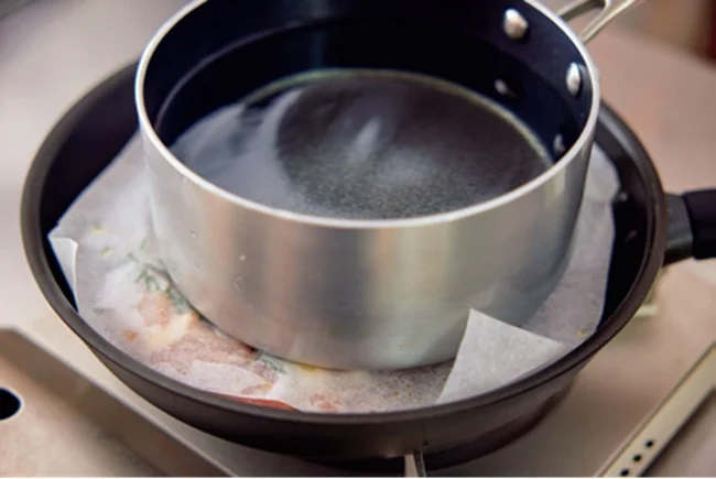 とり肉を焼くときは水を入れた鍋をのせておもしにする
