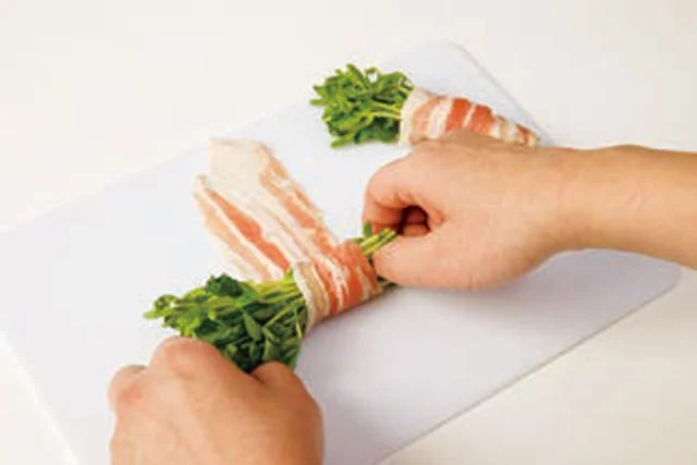 豆苗をそろえ、豚肉を少しずらしながら巻いていく