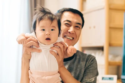 赤ちゃんを抱き上げるおじいちゃん（⇒次へ）