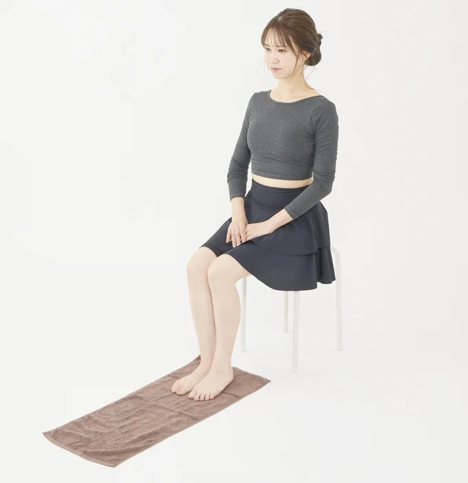  椅子に座り床にタオルを置く