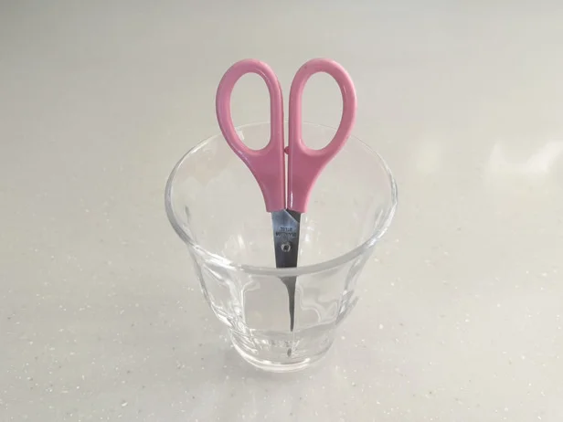 ハサミの刃が浸かる高さのコップにハサミを入れます（▶次へ）
