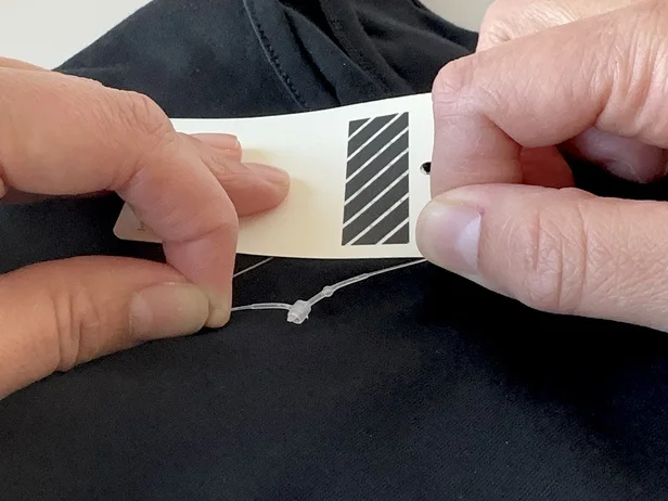ハサミがないとなかなか切れない商品タグのコード。実はある方法で簡単に切れる…！（▶次へ）