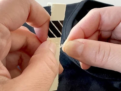 ねじれの起点が動かないように、指で押さえて固定するのがポイント（▶次へ）