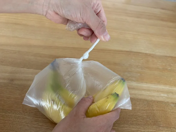 1、袋の口の部分を2～3cmくらい、ぐるぐるねじって、細く・固くする。（▶次へ）