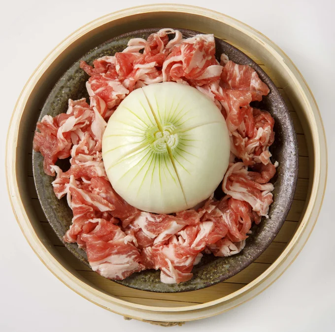 切り込みを入れた玉ねぎを真ん中に、まわりに豚肉を並べる