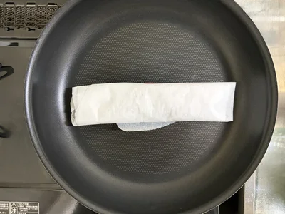 冷凍庫から出し、クッキングシートに包んだままフライパンの上へ（▶次へ）