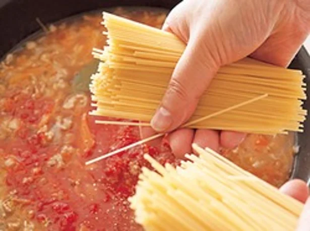 スパゲッティはソースの水分でゆでていく。半分に折って加えることで、フライパンからはみ出さず、効率よくゆでられる。