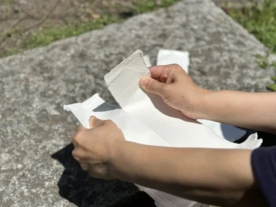 開いた牛乳パックを折り筋に沿って手で割きます（▶次へ）
